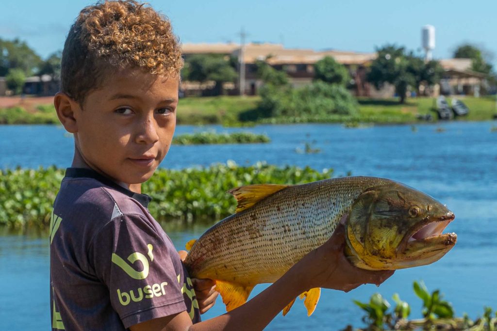 A boy holding a large fish with his hands
