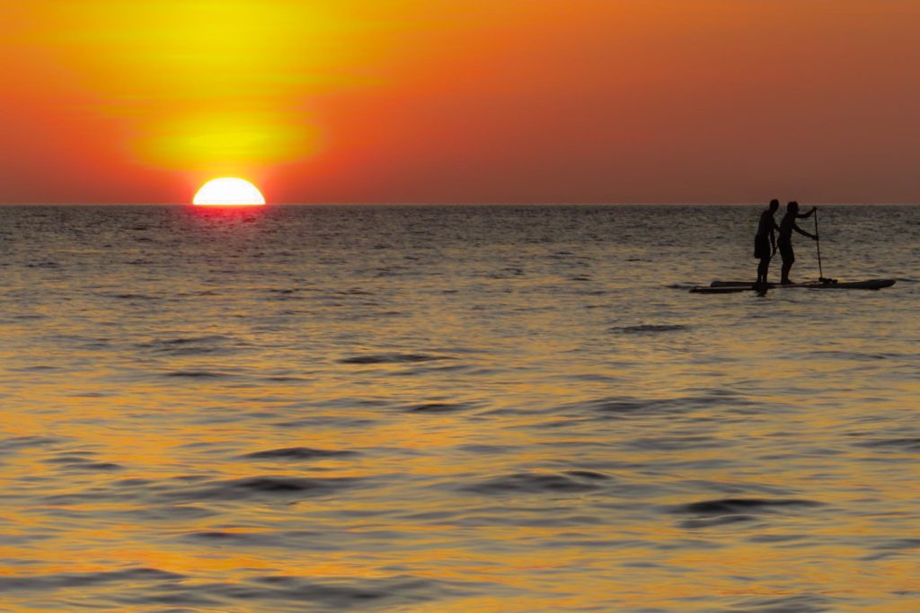 O pôr-so-sol de Koh Lanta e duas pessoas fazendo Stand-Up Paddle no mar