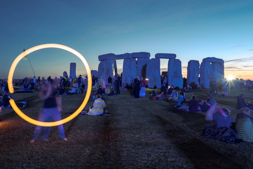 Um circulo de luz formado por alguém fazendo malabares em frente as pedras de Stonehenge durante o solstício de verão