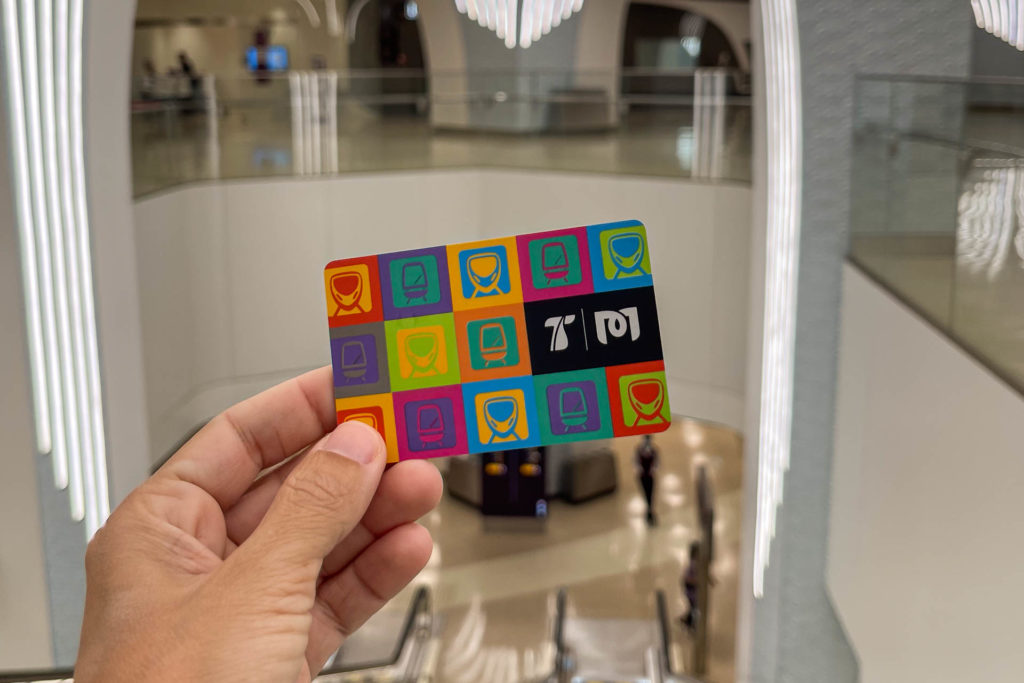 Uma mão segurando o cartão do metro dentro da estação de Doha