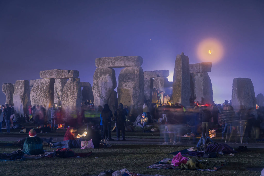 The moon rising behind the Stonehenge at night