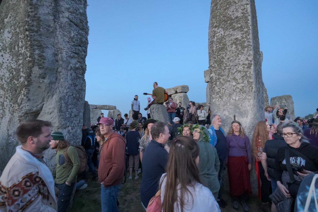 Man playing guitar on top of a rock at the summer solstice in Stonehenge