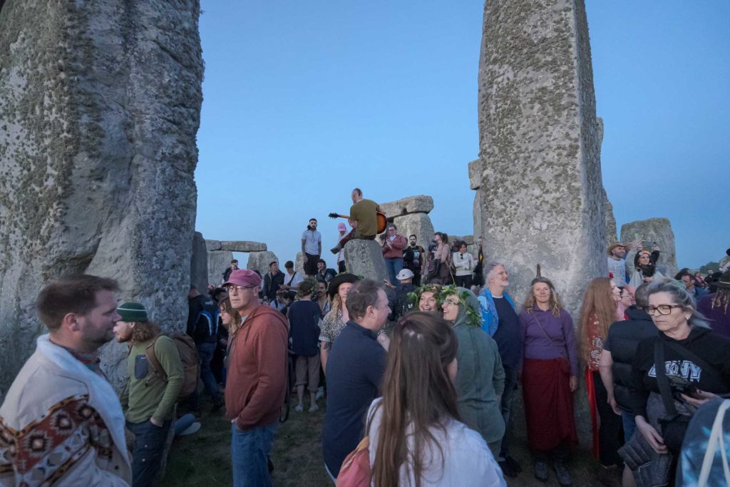 homem tocando violão de cima de uma das pedras de Stonehenge