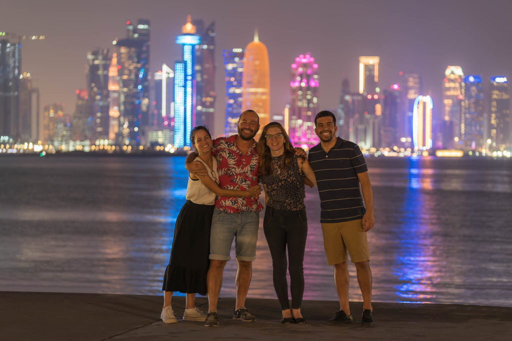 Tiago, Fernanda and two friends posing in front of the many buildings of Central Doha