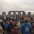 Muitas pessoas no meio das pedras de Stonehenge sendo observada de costas por uma outra pessoa