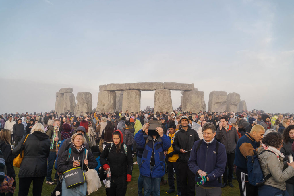 Muitas pessoas assistindo o nascer do sol na frente de Stonehenge durante o solstício de verão