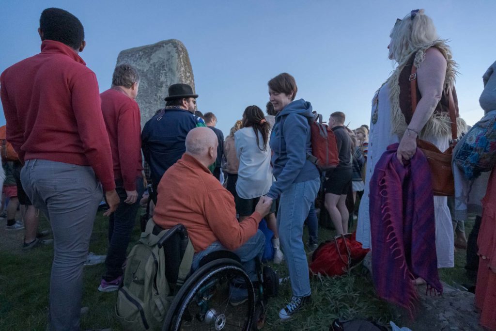 Um cadeirante em meio as pessoas no festival de solstício de verão de Stonehenge Inglaterra