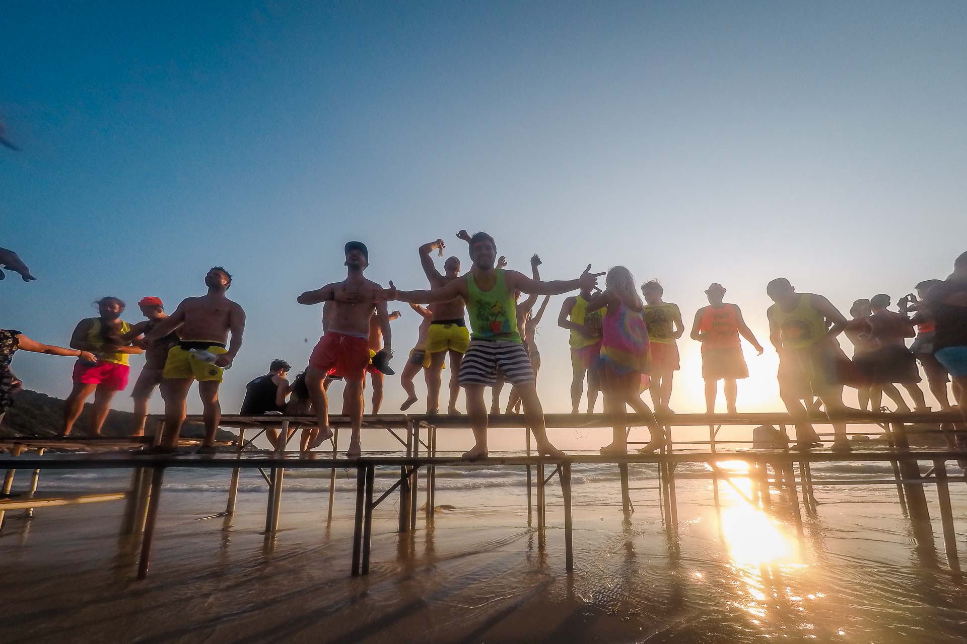 People dancing with the sunrise on top of a large table during the Full Moon Party