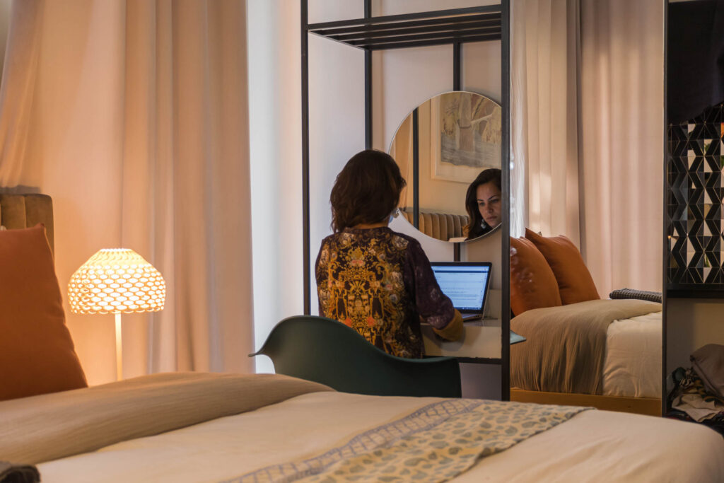 Fernanda sitting down near the bed of the room working on her laptop in the best boutique hotel of Tehran