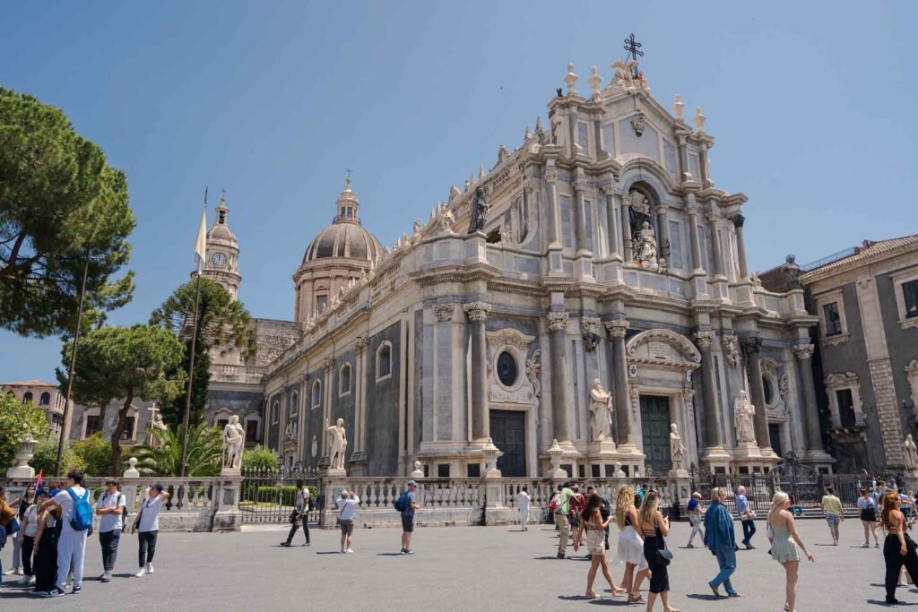 Catedral principal de Catania na praça da cidade com muitas pessoas passando em frente