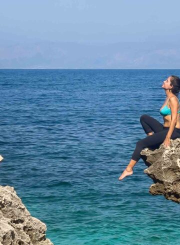 Fernanda sit in a rock in front of the sea in Sicily