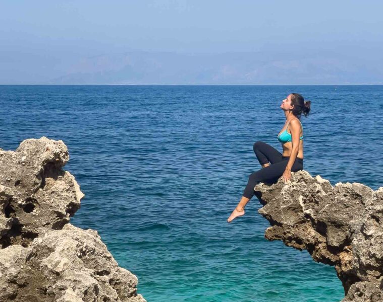 Fernanda sit in a rock in front of the sea in Sicily