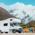 Motorhome camper van RV road trip on New Zealand. Couple on travel vacation adventure. Tourists looking at view of Aoraki Mount Cook National park and mountains next to rental car. Panoramic banner.