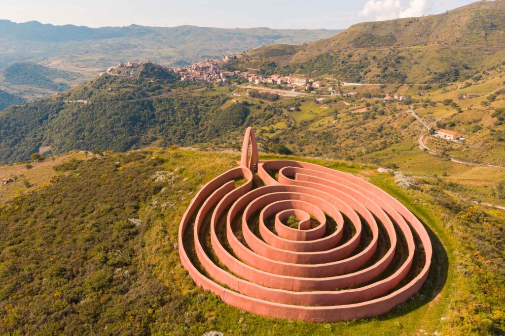 Um labirinto grande e rosa no topo da montanha, de frente para a cidade no meio da ilha da Sicília