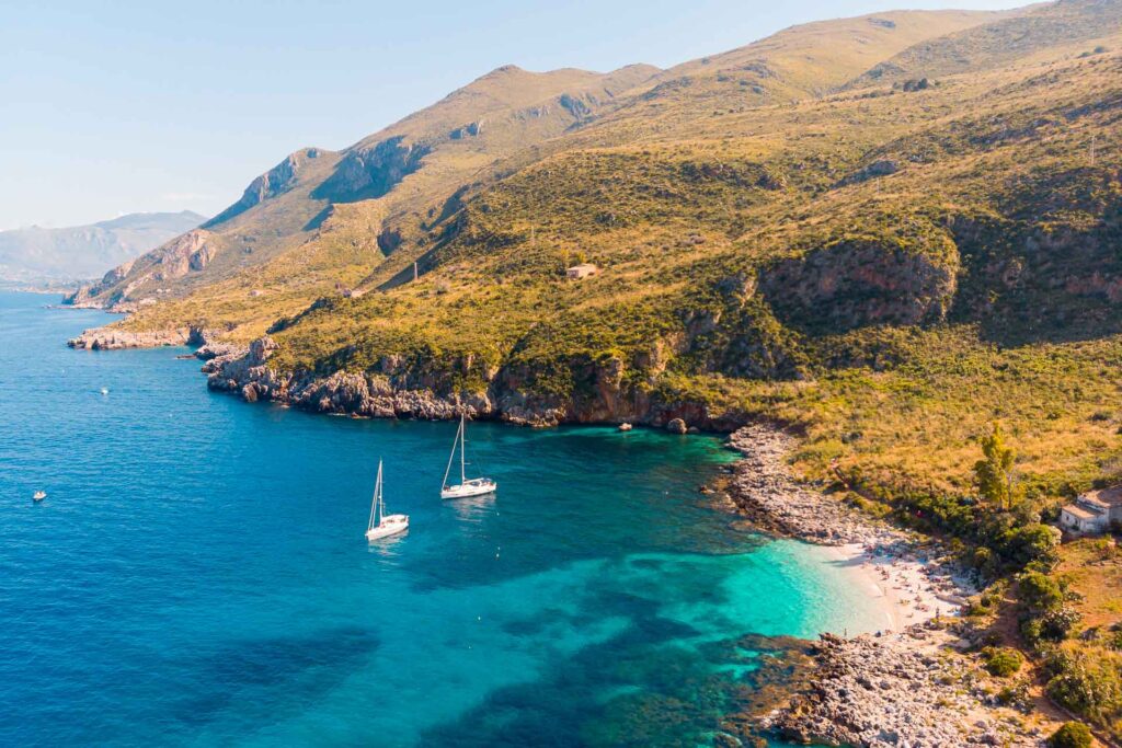 Vista aérea da praia do Parque Nacional de Zangaro na beira da montanha com uma água cristalina em São Vito Lo Capo, na Sicília