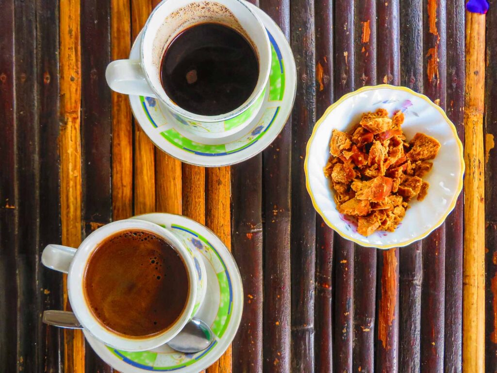 A bamboo table with two cups of lemur coffee and a portion of sugar from palm tree