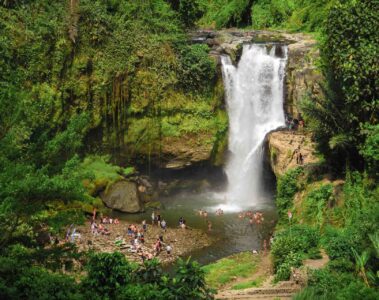 The large Tegenungan waterfall falling in a pool swimming by many people