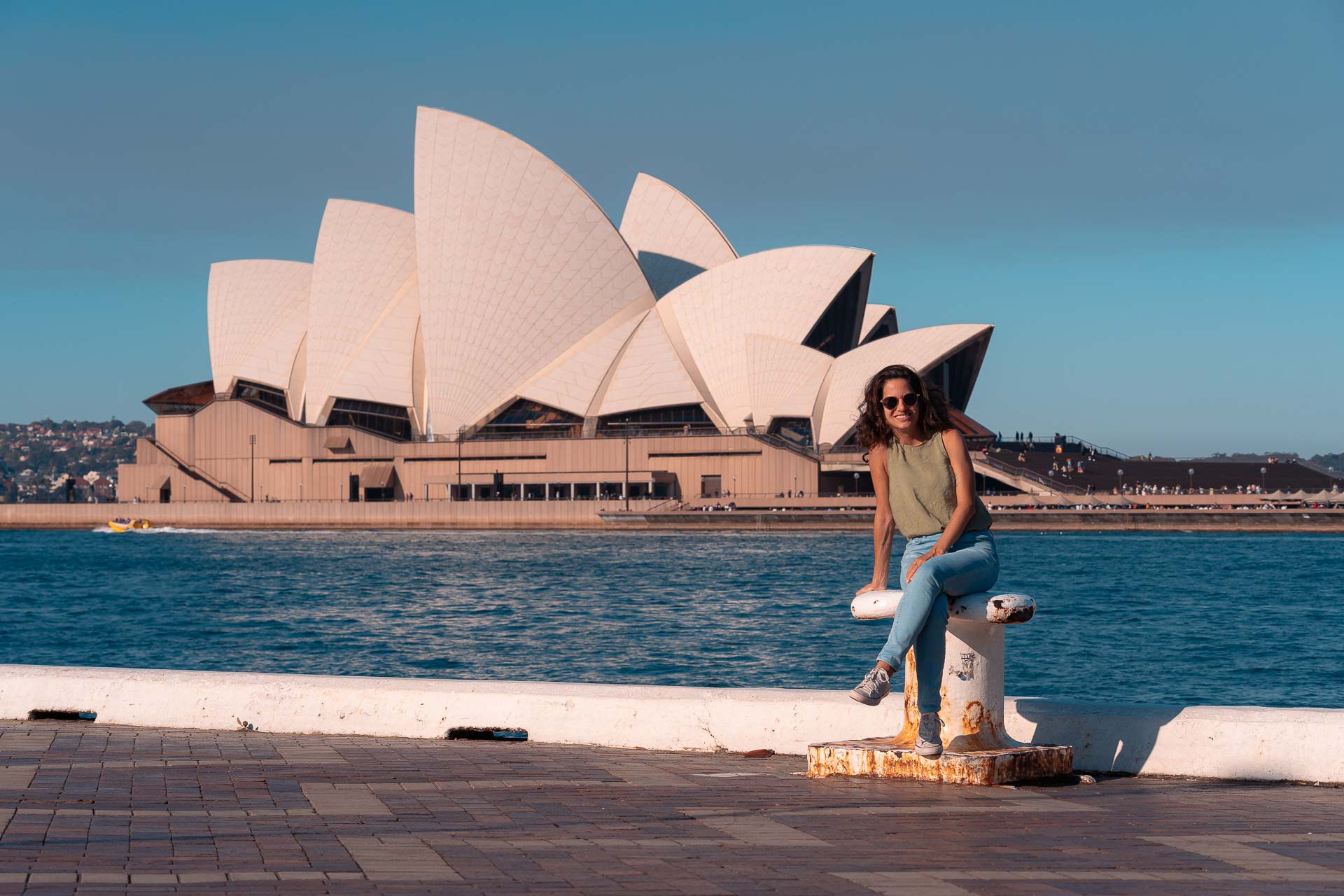 Fernanda sentada na frente da Ópera House de Sidnei do outro lado do porto