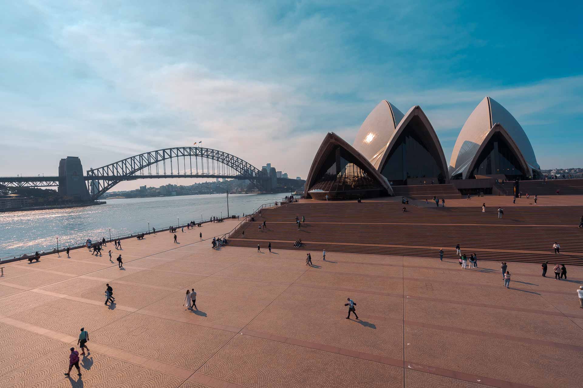 Vista do porto com a ponte de Sydney ao fundo e a Ópera House e seu pátio