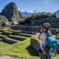 Blonde woman with camera taking pictures of machu picchu in a beautiful summer day with a blue sky.